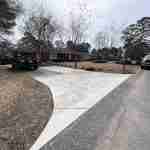 A curved driveway with trees and bushes in the background.