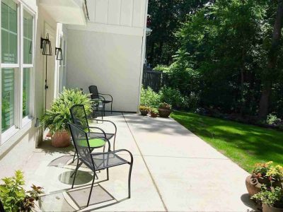 A patio with chairs and plants on the side of it.