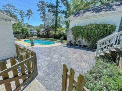 A pool and patio area with a fence.