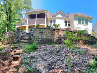 White house with stone retaining wall.