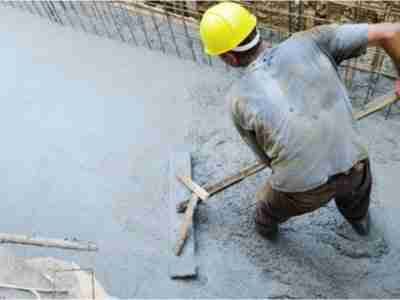 A construction worker is working on the sidewalk.