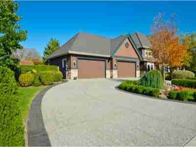 A large driveway with two garage doors and a house.